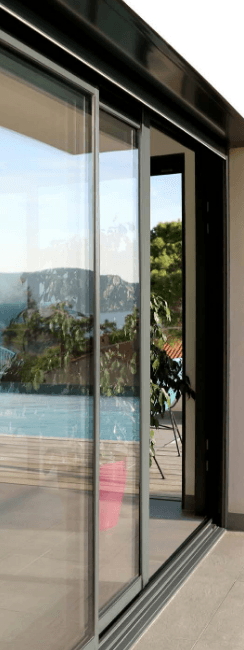 Baie coulissante aluminium noire ouverte sur une piscine et les montagnes
