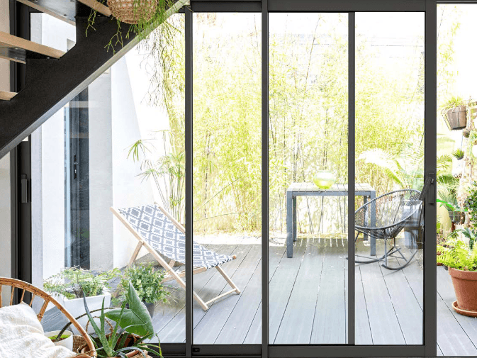 Baie vitrée aluminium noire de style atelier ouvrant sur une terrasse plantée de bambous
