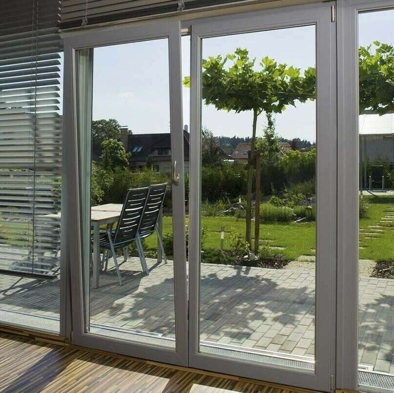Baie coulissante PVC grise ouvrant un séjour sur une terrasse et un jardin