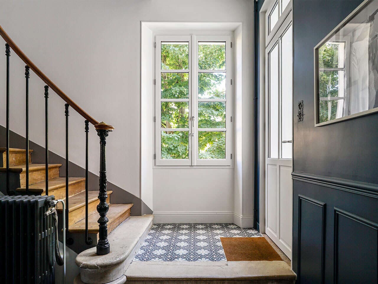 Porte-fenêtre bois blanche à petits bois dans une entrée avec escalier