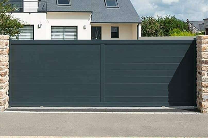 Portail coulissant en aluminium anthracite à lames horizontales devant une maison bretonne
