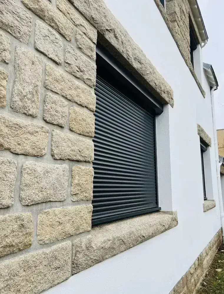 Volet roulant anthracite sur façade en pierre