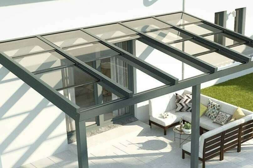 Pergola adossée à toiture polycarbonate translucide abritant un salon de jardin