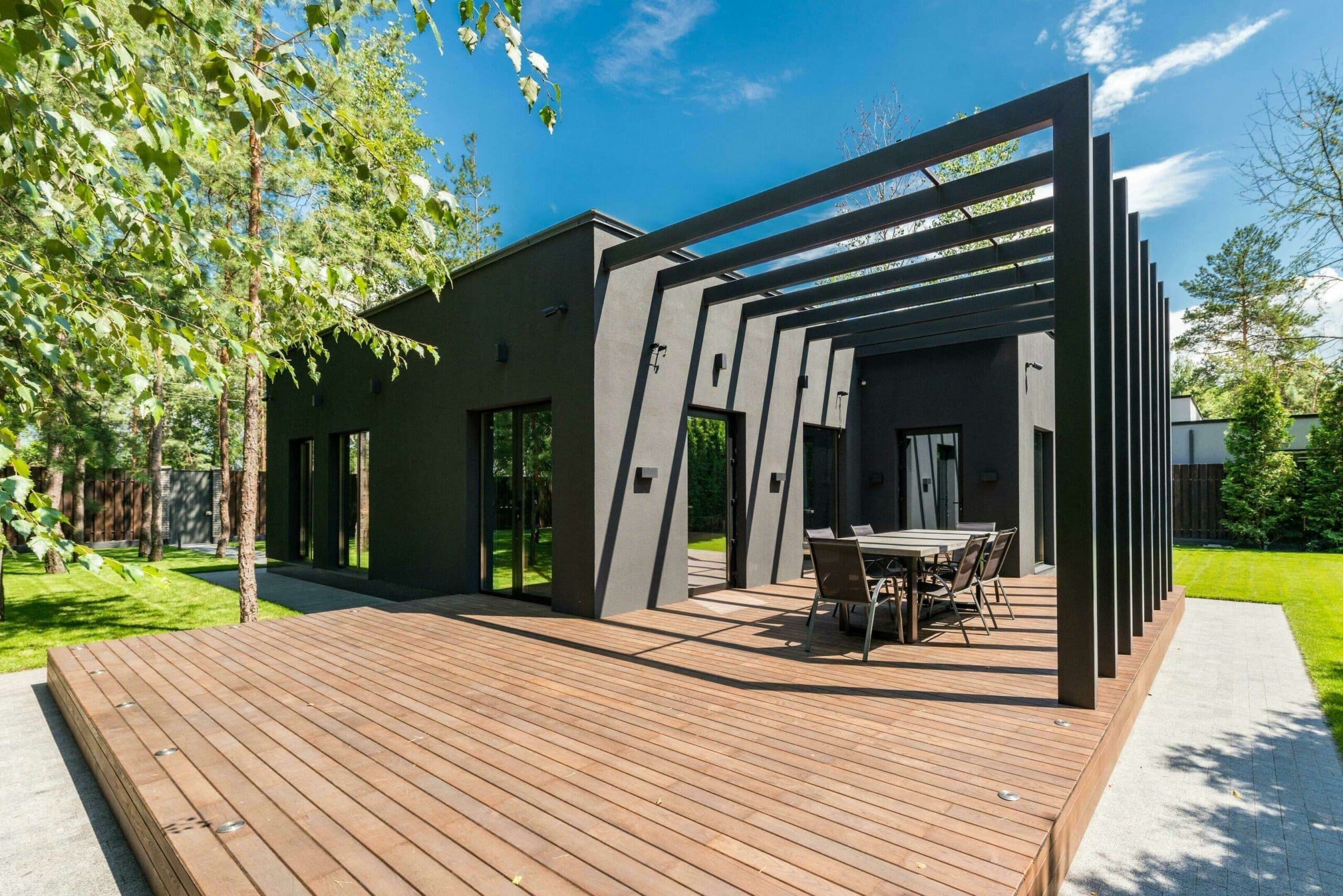 Pergola en aluminium noir adossée à une maison contemporaine, au-dessus d'une terrasse en bois