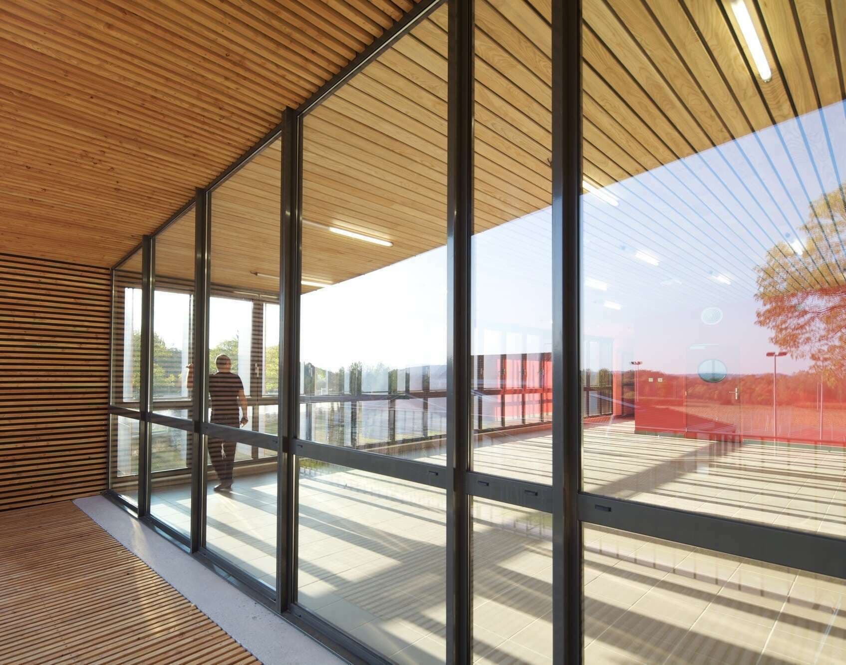 Grande baie vitrée à profilés aluminium noirs sous un plafond en lames de bois