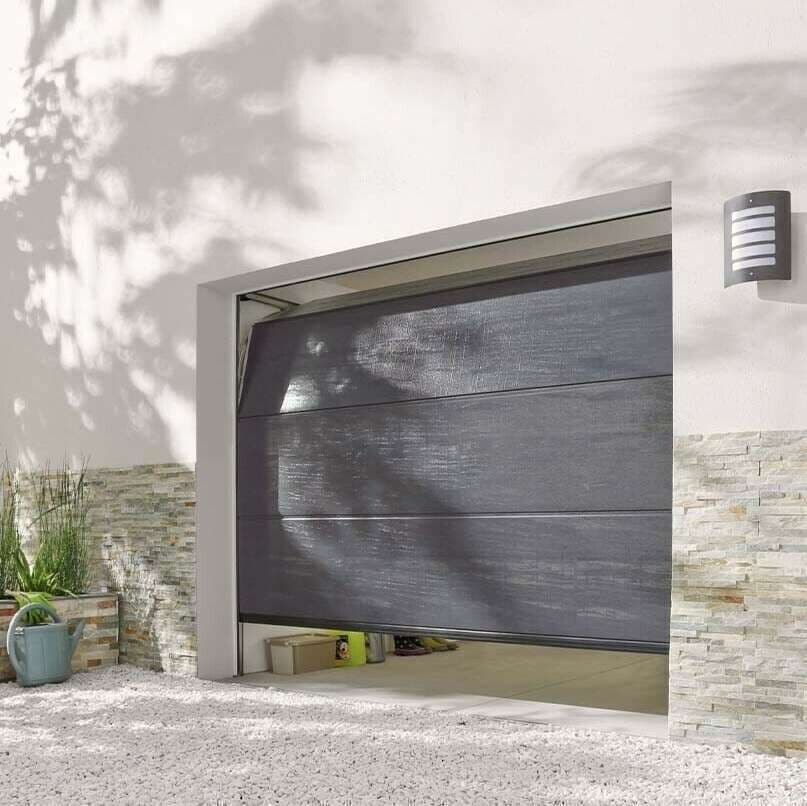 Porte de garage sectionnelle en acier anthracite entrouverte sur une façade blanche